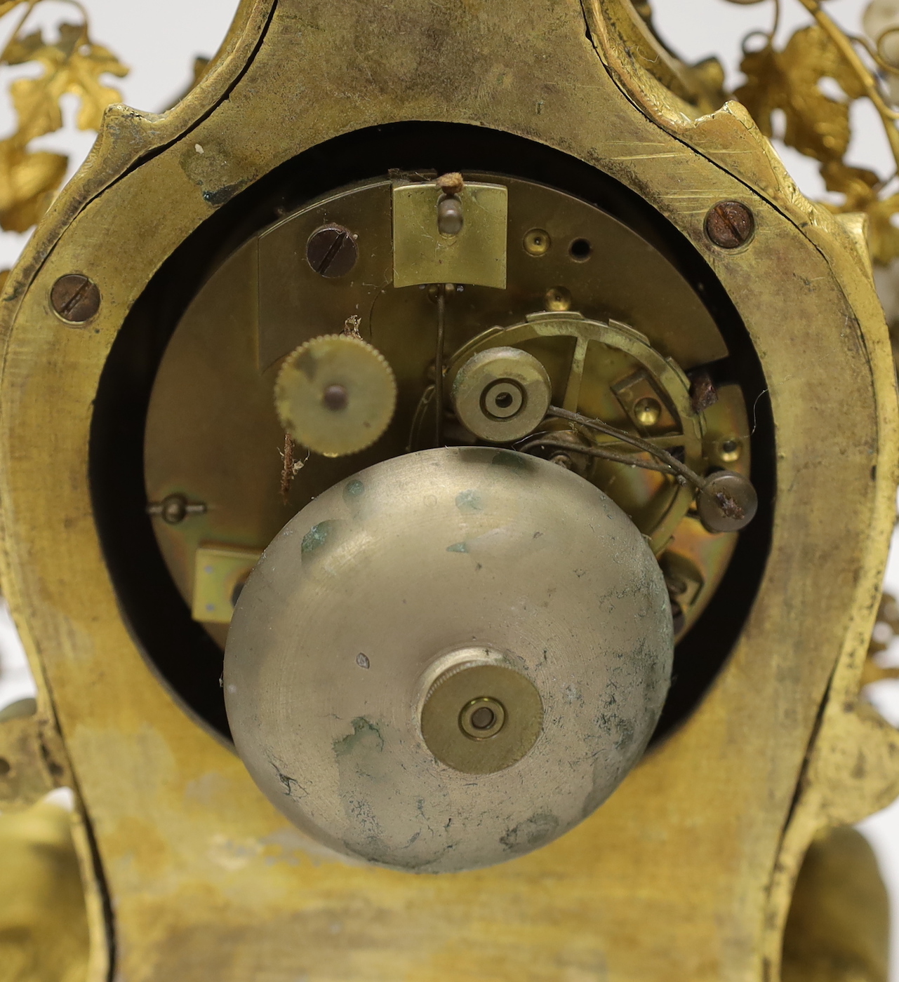A 19th century gilt bronze and porcelain mounted mantel clock, the waisted case cast with rocaille, embellished with porcelain flower heads, with circular white enamel Roman dial, the associated twin train movement with